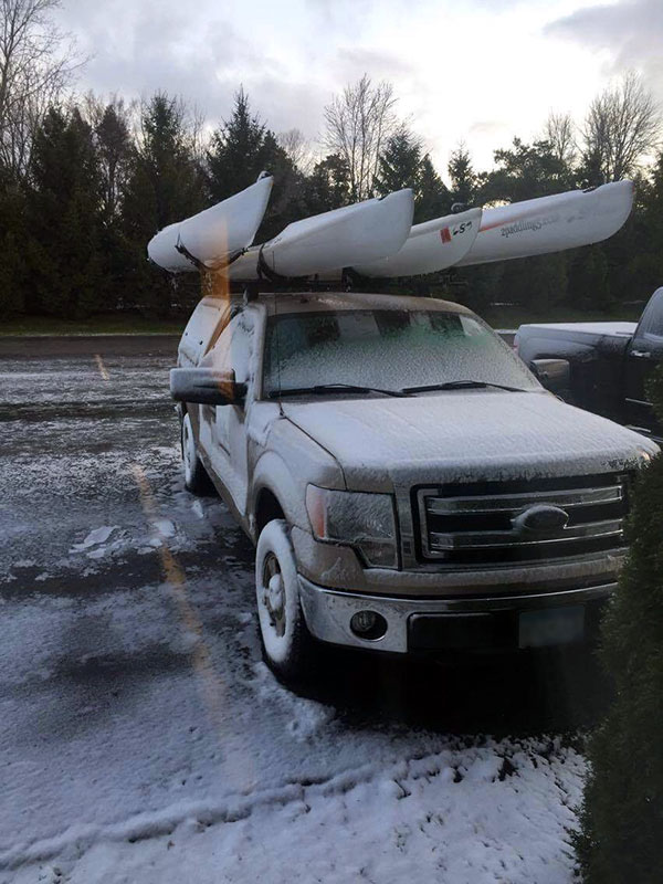 Snow on truck with kayaks on rack full size picture.