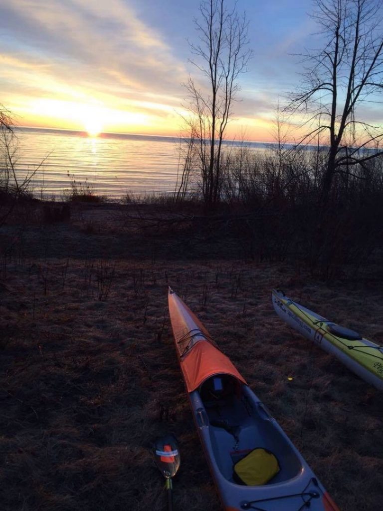 Kayaks by lake Huron during a morning sunrise.
