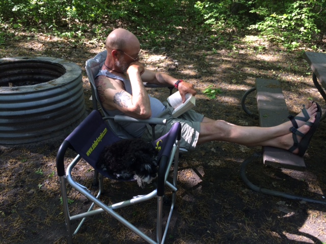 Joe Zellner and Izzy the dog chillin on a campsite.