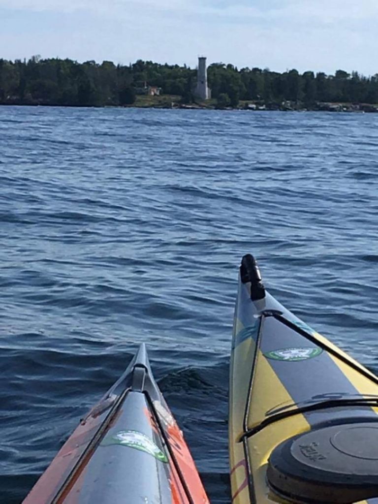 Poverty Island Lighthouse viewed from front of 2 kayaks.